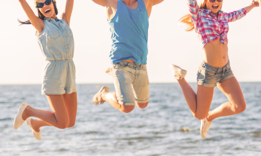 Three people joyfully jumping on the beach at sunset.