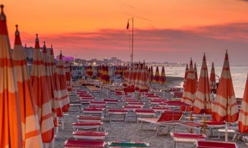 Beach at sunset with closed orange umbrellas.