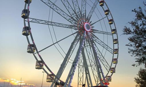 Grande roue au coucher du soleil avec lumières allumées.